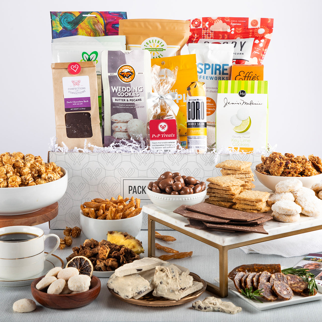 Open gift basket labeled ‘Above and Beyond’ with heirloom popcorn, dried mango, chocolate meltaways, and crackers.