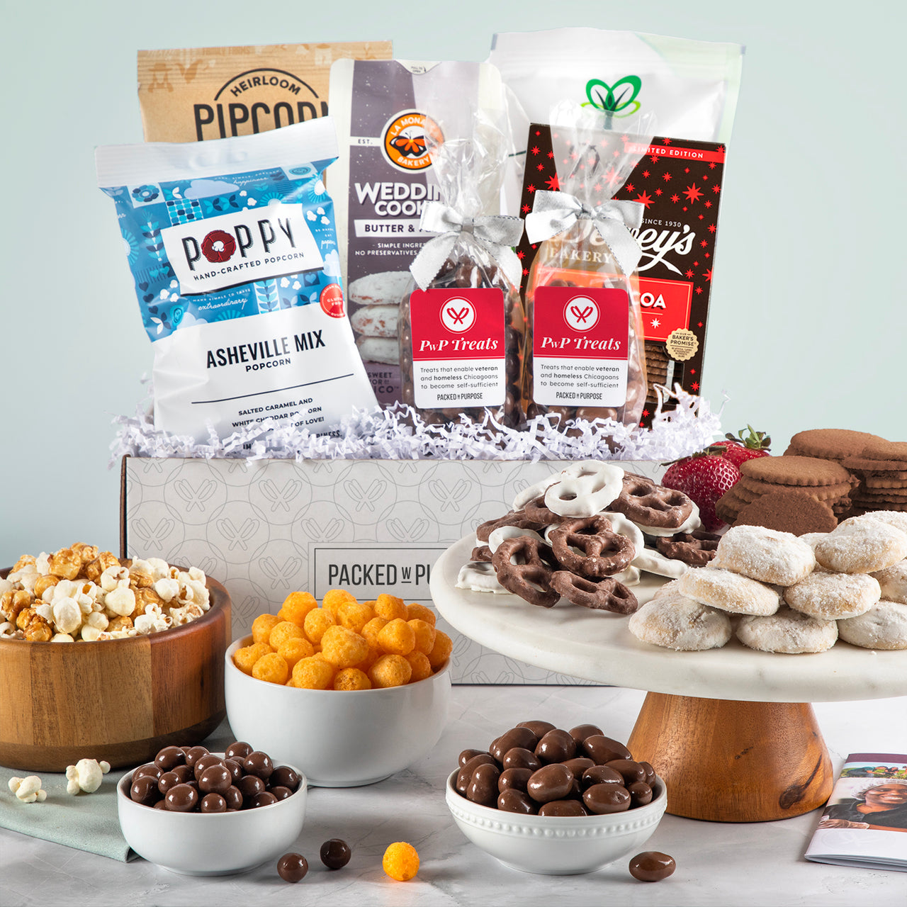 Open gift basket labeled ‘Heartfelt Thanks’ with cookies, toffee, chocolate pretzel bites, popcorn, and cheese balls.