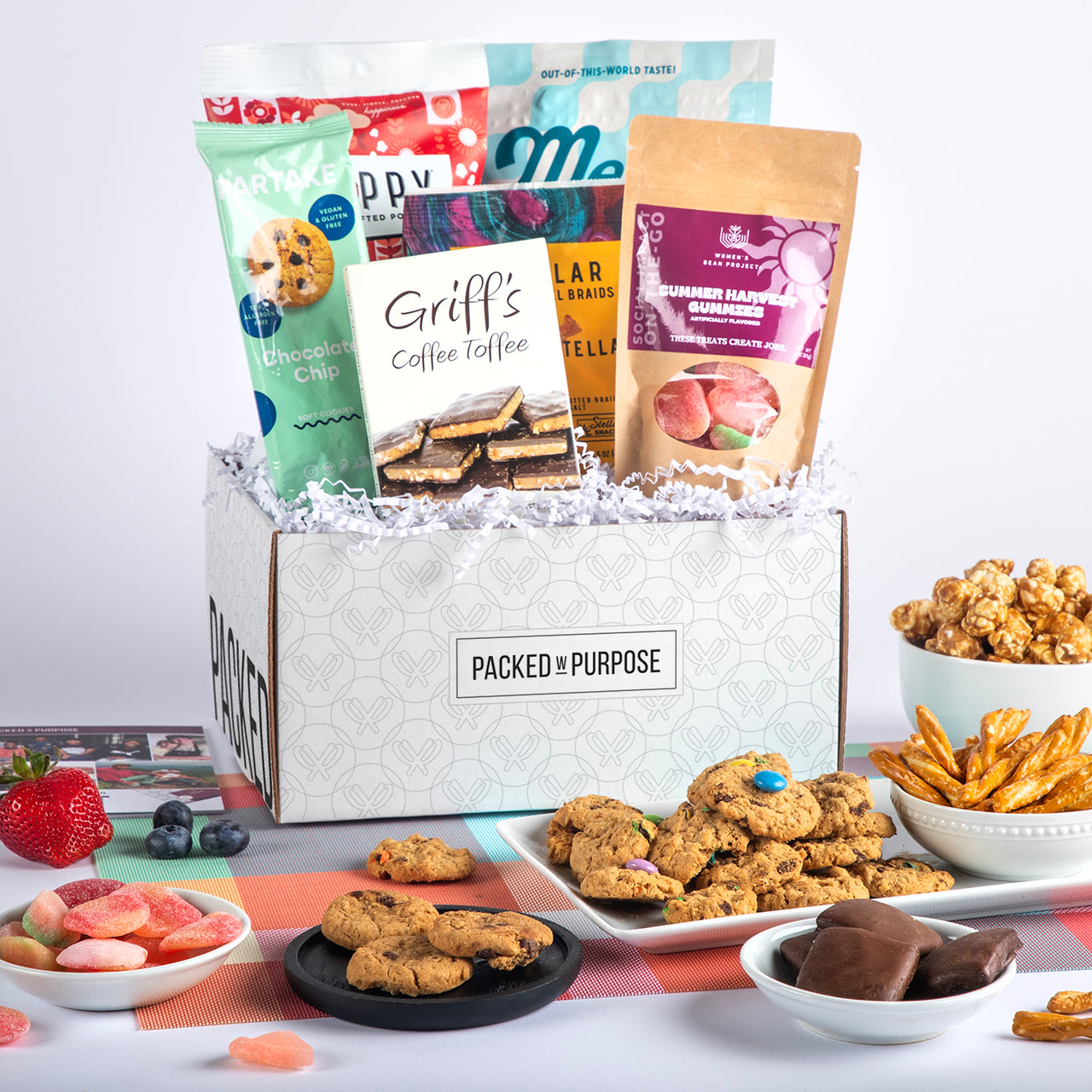 Open gift basket labeled ‘Make Them Smile’ with cookies, chocolate, sour gummies, and crunchy pretzels.
