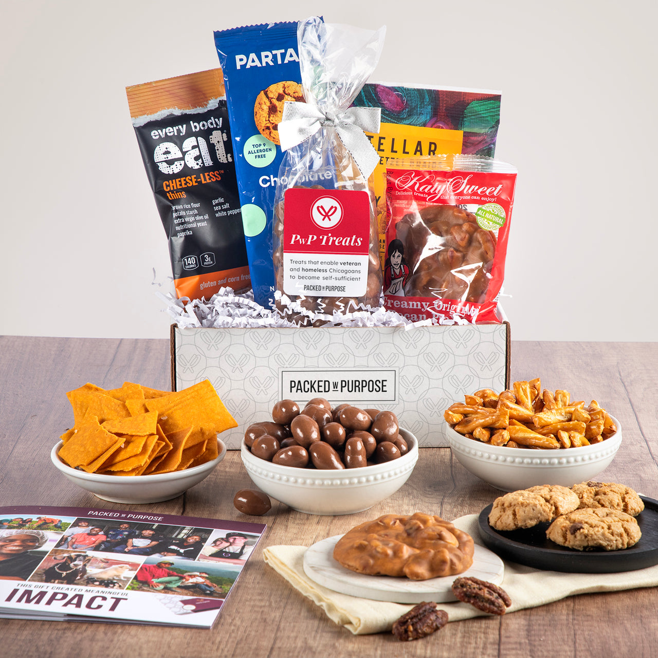 Open gift basket labeled ‘Many Thanks’ with bite-sized cookies, praline, cheese balls, and chocolate truffle bar.