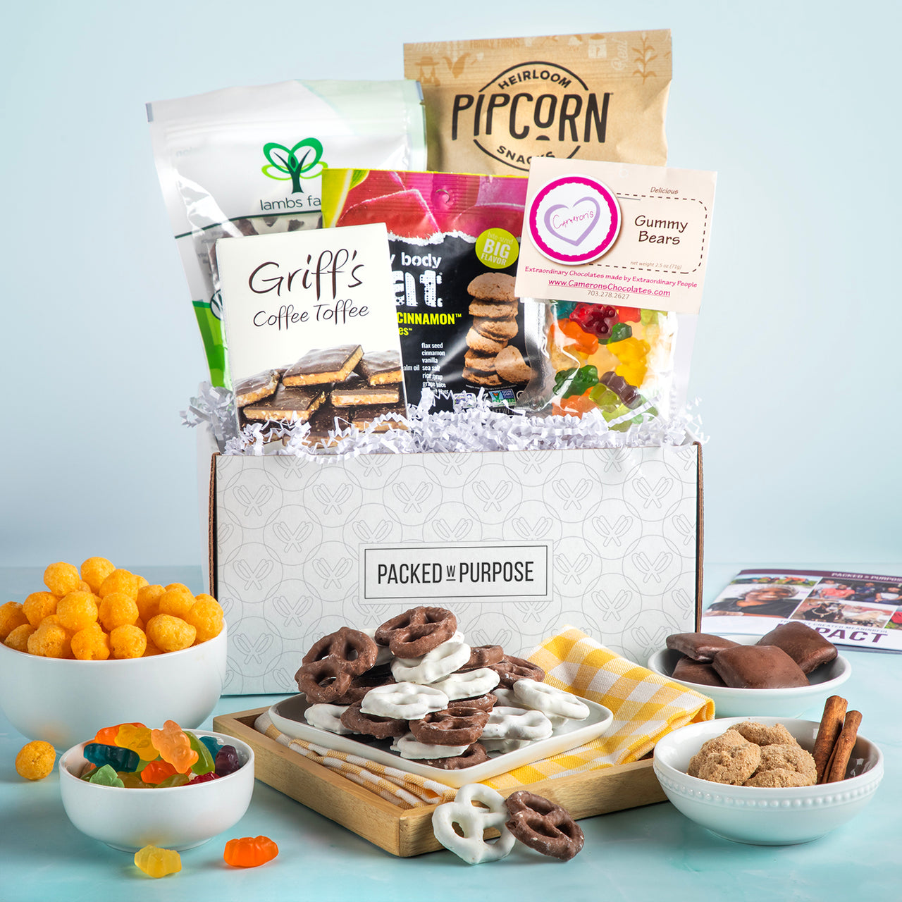 Open gift basket labeled ‘Spread Some Cheer’ with Oreo bark, cookies, handcrafted toffee, and gummies.